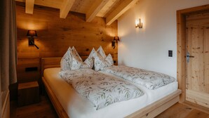 A wooden bedroom with a bed, two nightstands, and a wooden door. - Chalet Salzach Near Ski Lift & Spa (Bramberg am Wildkogel)