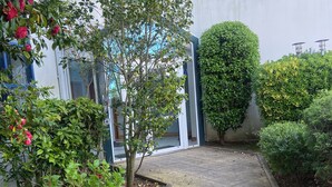 Un chemin pavé mène à un bâtiment à la façade blanche et aux encadrements de fenêtres verts.