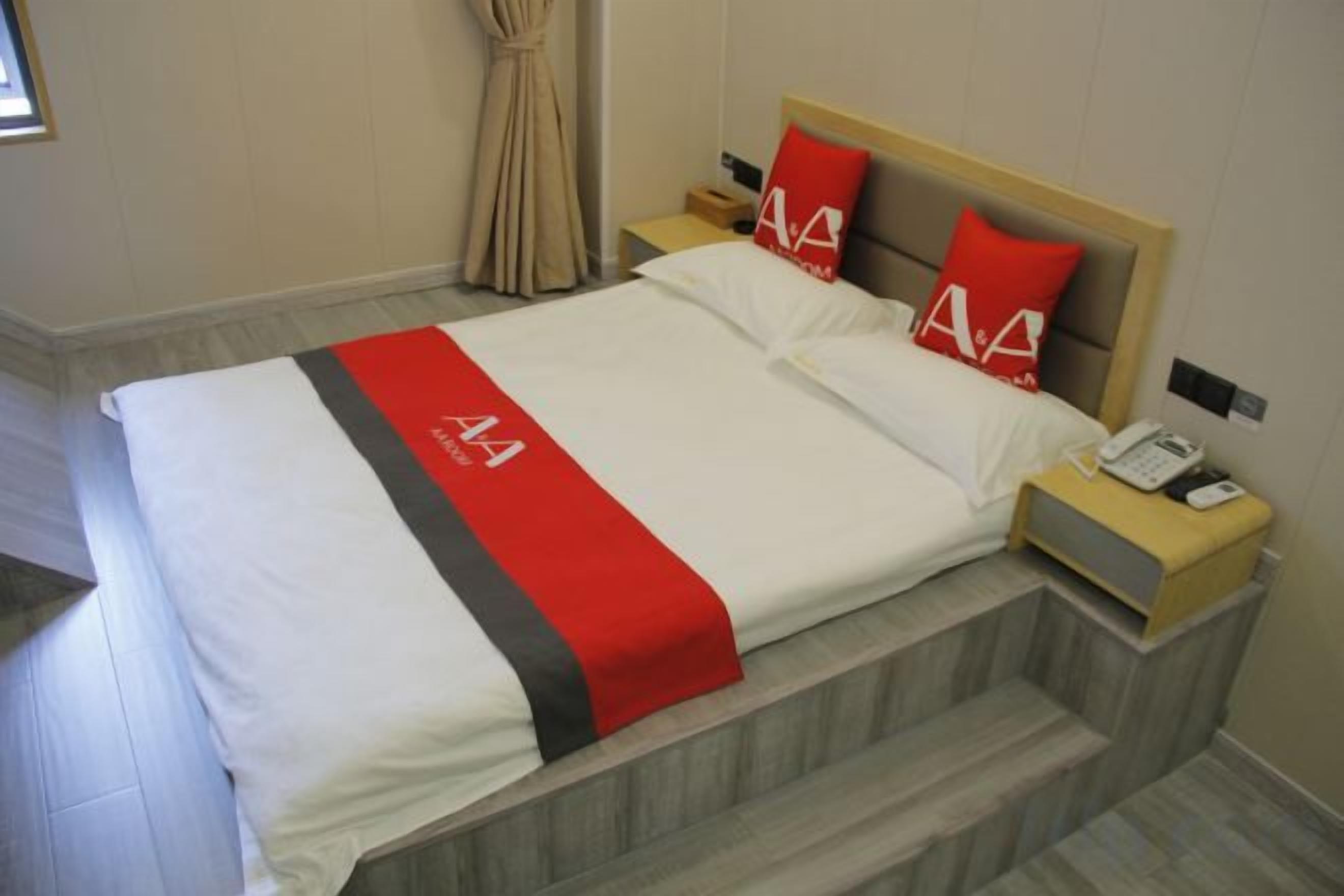 Een hotelkamer met een bed, nachtkastje en telefoon.