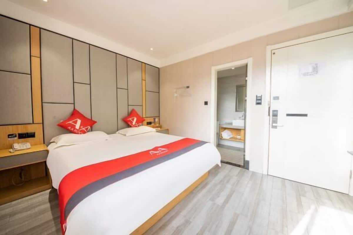 A hotel room with a large bed, two nightstands, a wardrobe, and a mirror.
