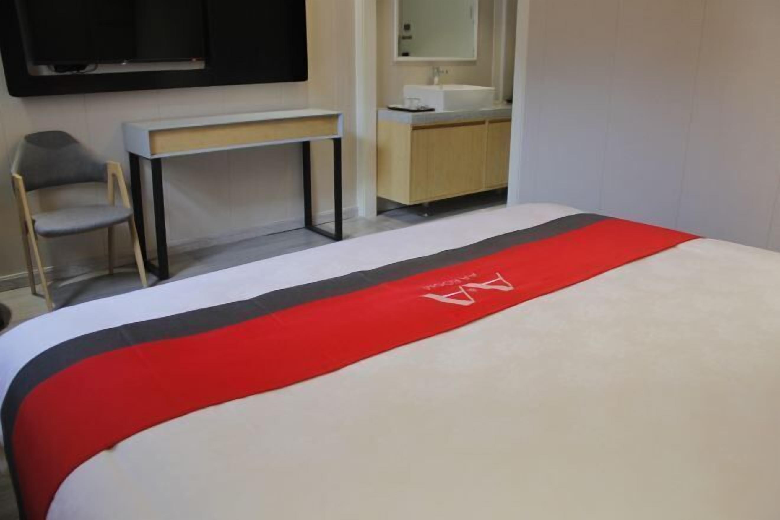 Una habitación de hotel con una cama, un escritorio, una silla, un lavamanos y un espejo.