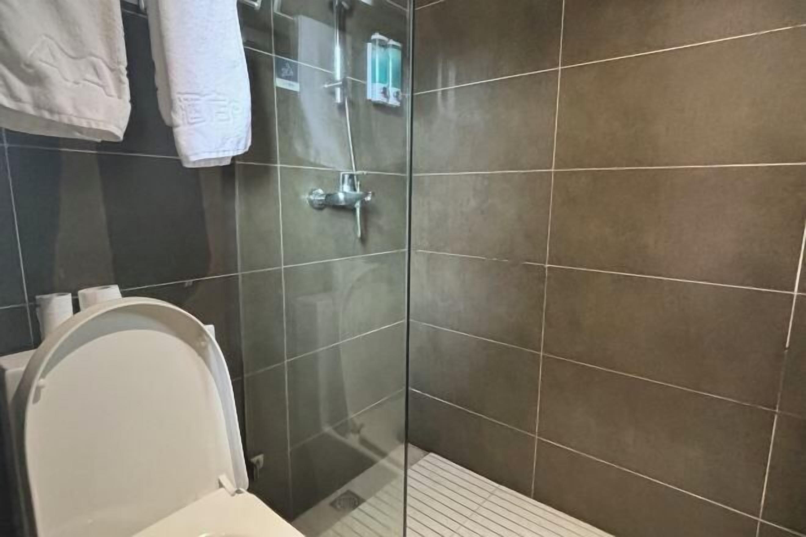 A bathroom with a glass shower enclosure, a toilet, and a towel rack.