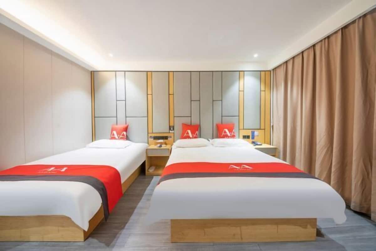 A hotel room with two beds, a nightstand, a mirror, and a curtain.