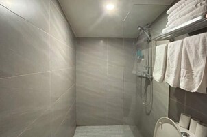 Un baño moderno con cabina de ducha de vidrio, inodoro y toallero con toallas dobladas.