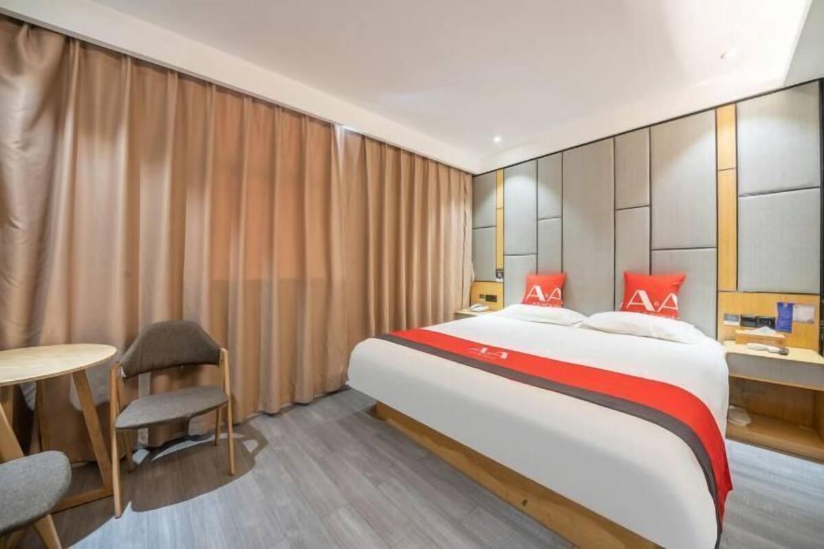 A hotel room with a bed, a desk, a chair, and a curtain.