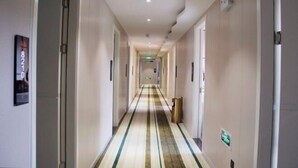 A hotel hallway with a striped carpet, doors on both sides, and a trash bin on the right. - AA Hotel Chain (Quzhou International Financial Center Shuiting Branch) (Quzhou)