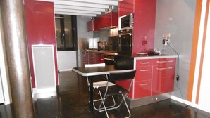 A compact kitchen with red cabinets, a microwave, and a small refrigerator. - Le Clos D'ondres -spa Privé (Sarrant)