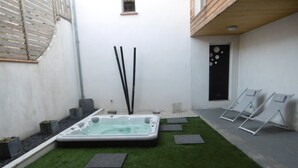 A spa area with a hot tub, artificial grass, and seating. - Le Clos D'ondres -spa Privé (Sarrant)