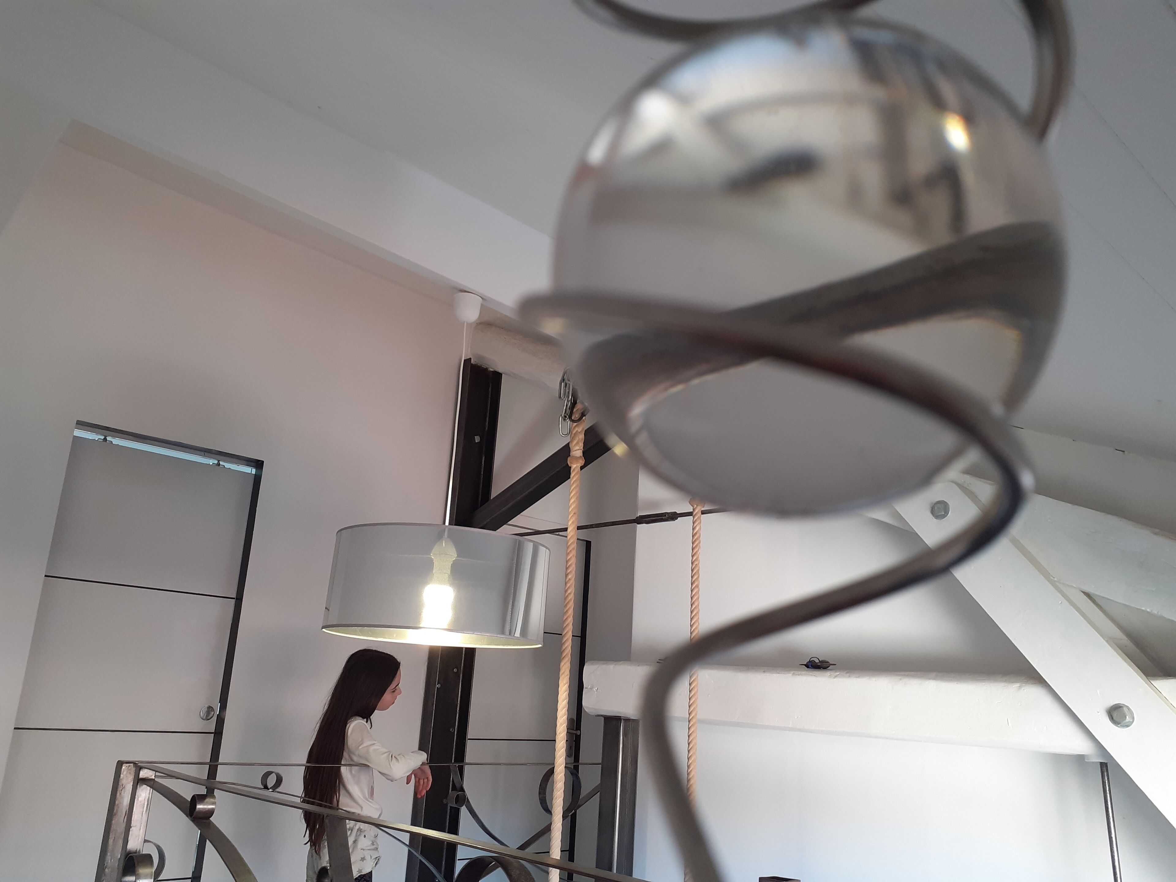 A modern interior with a staircase, a hanging light fixture, and a person standing on the stairs.