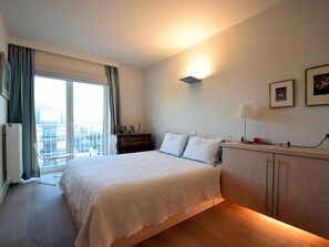A hotel room with a large bed, a dresser, a desk, and a window with curtains. - Beachfront Bliss in De Haan (De Haan)