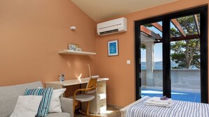 A bedroom with a bed, a desk, a chair, a sofa, and a window with a view of the sea. - Beachfront Villa Zara  (Mimice)