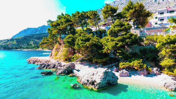 A coastal area with clear turquoise waters, rocky shoreline, and buildings with balconies overlooking the sea. - Beachfront Villa Zara  (Mimice)