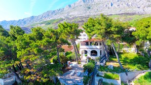 A villa with a stone facade, a red-tiled roof, and a central courtyard with a staircase leading to a terrace. - Beachfront Villa Zara  (Mimice)