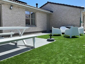 A patio area with a picnic table and chairs, a small round table, and a lawn. - Holiday Home in Koksijde Near Sint-andre Beach (Koksijde)
