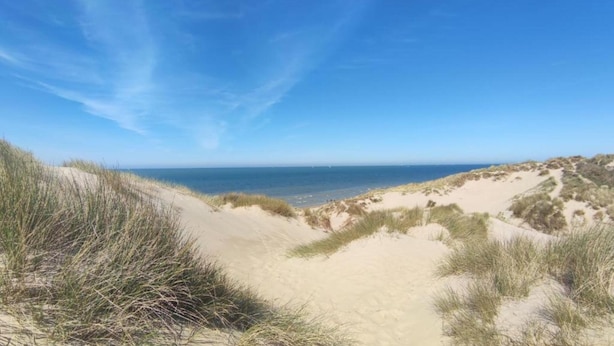 Un paysage côtier avec des dunes de sable et un ciel bleu dégagé.