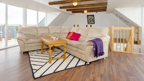 A spacious living room with a beige sectional sofa, a wooden coffee table, and a black and white rug. - 6 Person Holiday Home in Harboore (Harboore)