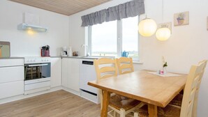 A modern kitchen with white cabinets, a wooden dining table, and two chairs. - 6 Person Holiday Home in Harboore (Harboore)