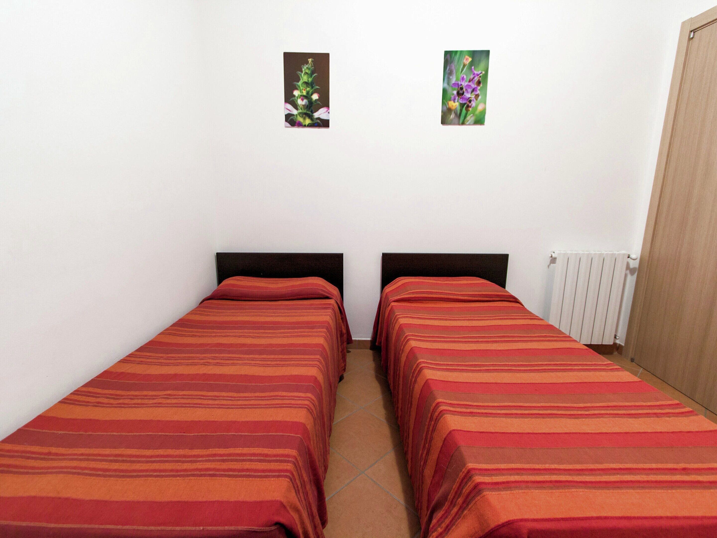 A room with two single beds, a radiator, and two small framed pictures on the wall.