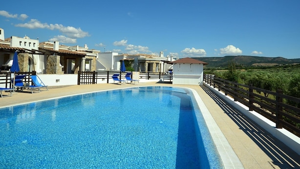 A swimming pool with blue water, surrounded by a wooden deck and a white fence. - Villa in Alghero With Pool & Near Town (Alghero)