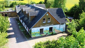 Une rangée de maisons en bois aux toits inclinés, entourées de verdure et de champs.