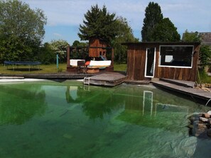 A swimming pool with a wooden deck, a small wooden cabin, and a lounge area with a slide. - Haus Sommerwind OG Comfortable Vacation Home (Klink)