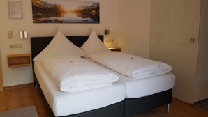 A double bed with white linens, a wooden headboard, and a nightstand with a lamp. - am Buchbrunnen Comfortable Holiday Residence (Pfronten)