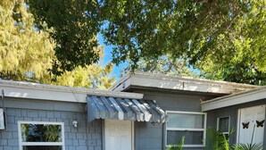 A residential house with a garage, two blue chairs, and potted plants. - Quaint studio (Largo)