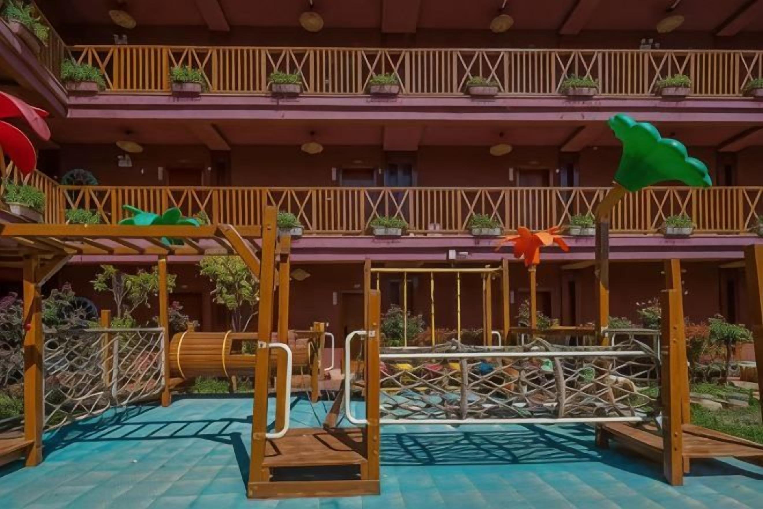 Zona de juegos al aire libre con varias plataformas, estructuras de madera y plantas en macetas.