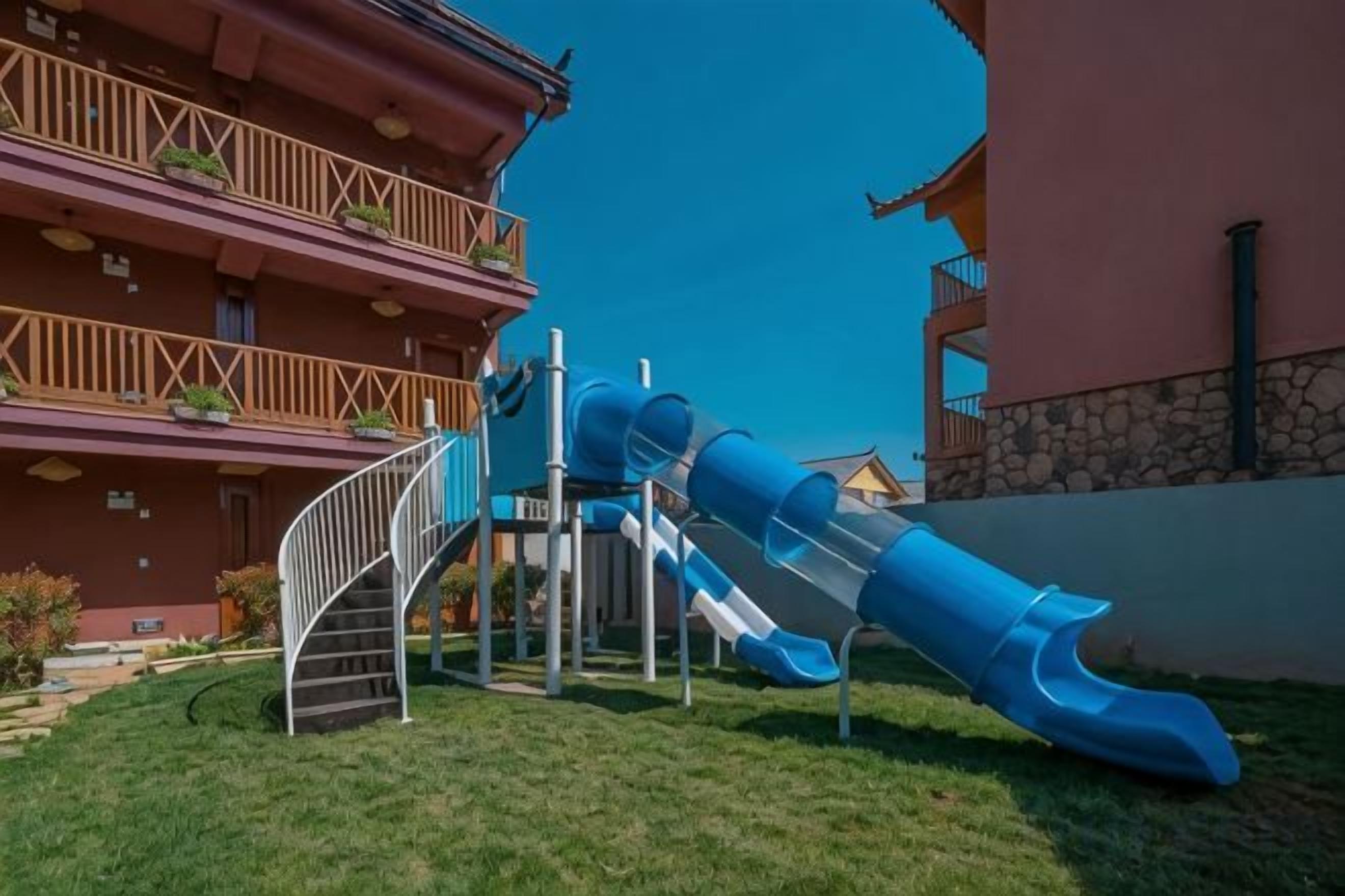 Un immeuble à plusieurs étages, doté d’un toboggan bleu et d’un escalier menant aux étages supérieurs.