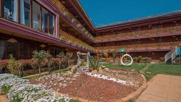 Un hotel con varios balcones, un patio central con un jardín circular y un cielo despejado.