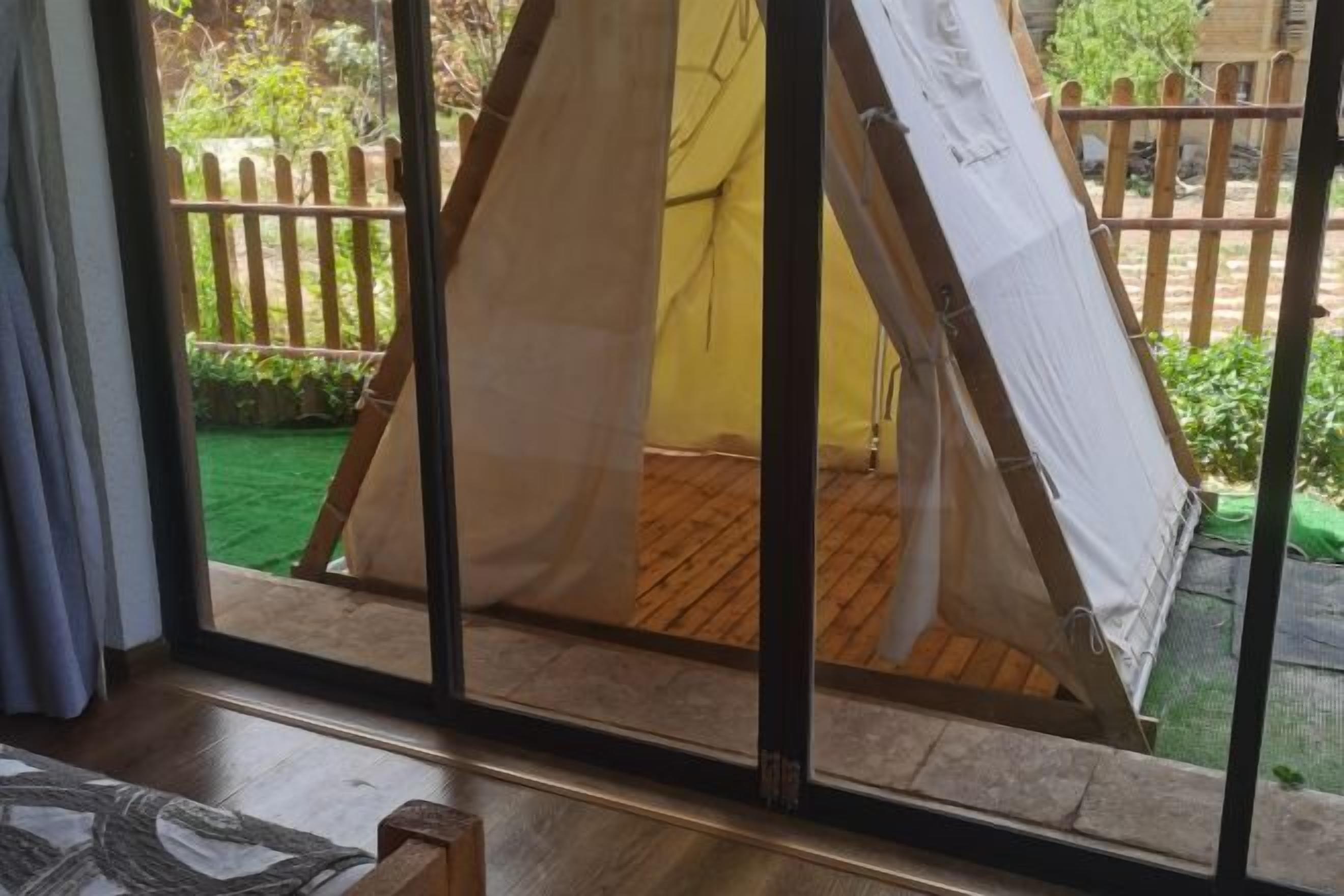 A room with a large window overlooking a wooden deck and a fenced garden.
