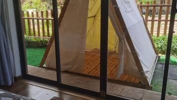 A room with a large window overlooking a wooden deck and a fenced garden.