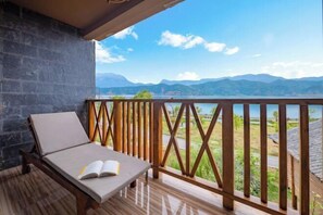 Un balcón con barandilla de madera, una silla de lounge y un libro abierto.