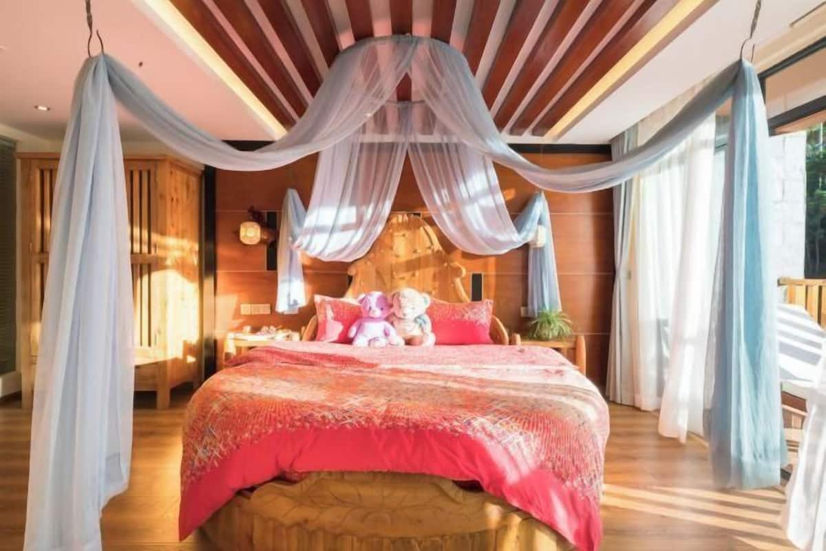 Quarto com cama de dossel, painéis de madeira, mesa de cabeceira e um urso de pelúcia.