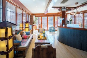 A hotel lobby with a reception desk, seating area, and large windows.