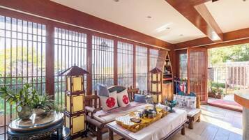 Une pièce de style japonais traditionnel, avec un sol recouvert de tatamis, une petite table sur laquelle est disposée une assiette de nourriture, et une vue sur un jardin à travers des panneaux coulissants.