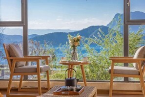 Una habitación con dos sillas de madera, una mesita con un florero y una bandeja con teteras.