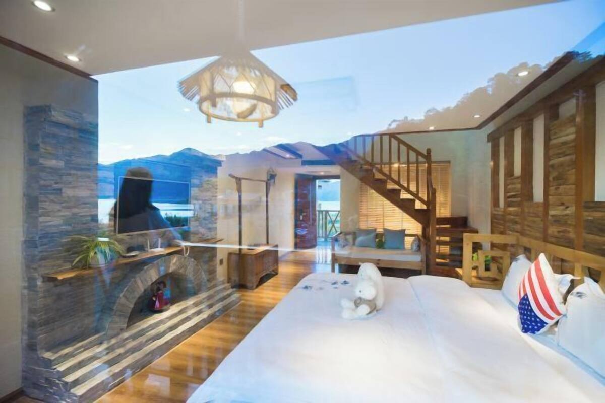 Quarto com cama grande, lareira, vista para as montanhas e escada de madeira.