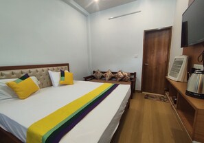 A neatly arranged bedroom with a bed, a television, and a coffee maker.