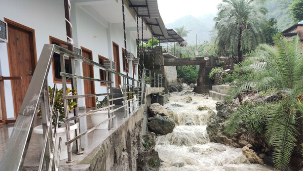 A hotel with a stone staircase leading to a balcony overlooking a cascading waterfall. - Hotel StudioZ Sahastradhara (Dehradun)