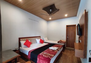 A hotel room with two beds, a wooden ceiling, a TV mounted on the wall, and a desk.