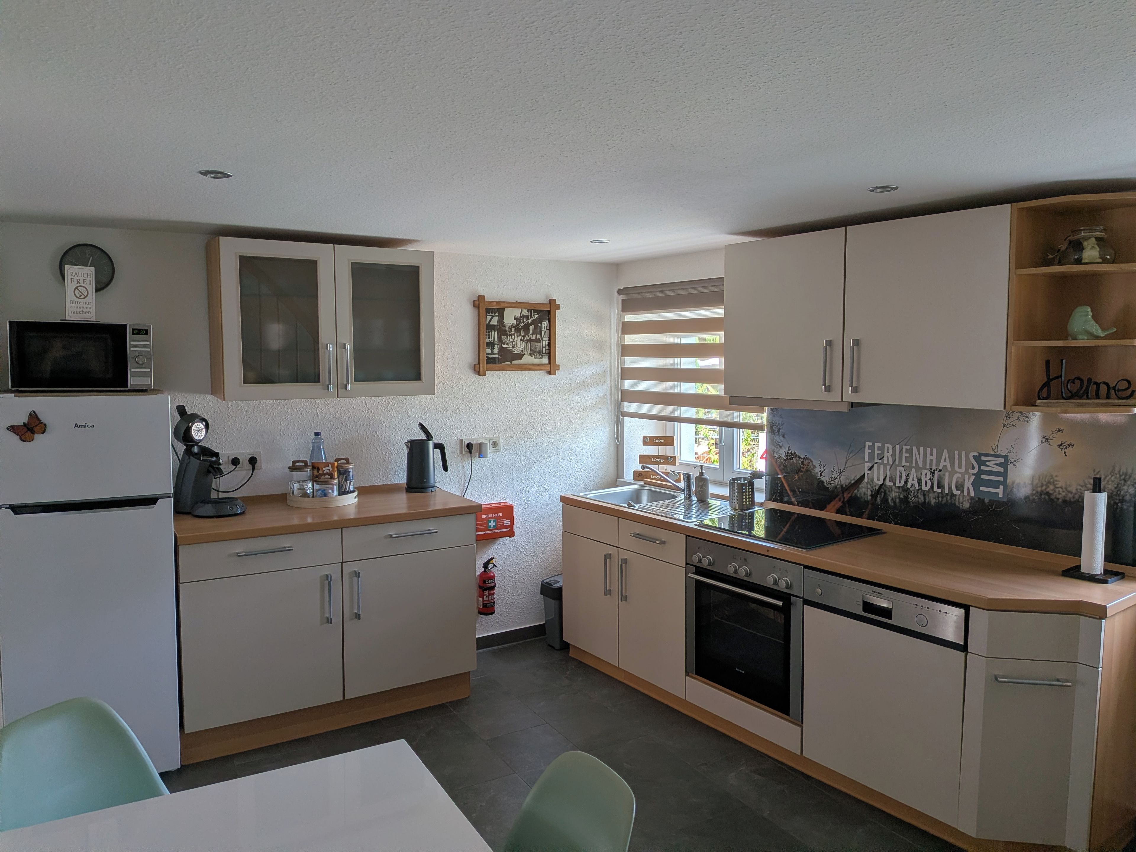 A compact kitchen with a microwave, coffee maker, and a sink. There is a fire extinguisher and a window with blinds.