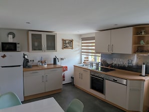 A compact kitchen with a microwave, coffee maker, and a sink. There is a fire extinguisher and a window with blinds. - Ferienhaus Fuldablick Das Ferienhaus Inmitten der Altstadt von Rotenburg /fulda (Rotenburg an der Fulda)
