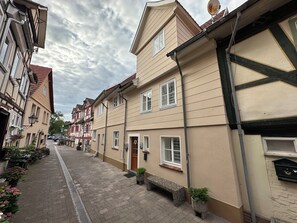 Une rue bordée de bâtiments de style européen traditionnel, avec un banc et des plantes en pot.