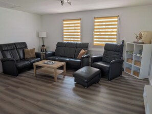 A modern living room with a sectional sofa, a coffee table, and a bookshelf.
