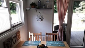A dining area with a wooden table, two chairs, and a decorative wall with a clock and shelves. - Chrissi's Baltic Sea Nest (Scharbeutz)