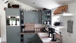 A compact kitchen with grey cabinets, a built-in oven, and a coffee machine. - Chrissi's Baltic Sea Nest (Scharbeutz)