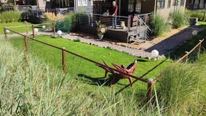 A row of modern cabins with a covered porch, a fenced garden area, and a gravel path. - Chrissi's Baltic Sea Nest (Scharbeutz)