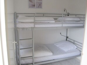 A bunk bed with white bedding and a small shelf unit. - 1 From Fam. Moritz Koopman (Petten)