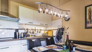 A modern kitchen with white cabinets, a black countertop, and a hanging light fixture.